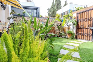 Un jardín bien cuidado con un muro de piedra, un portón de madera y una gran variedad de plantas.