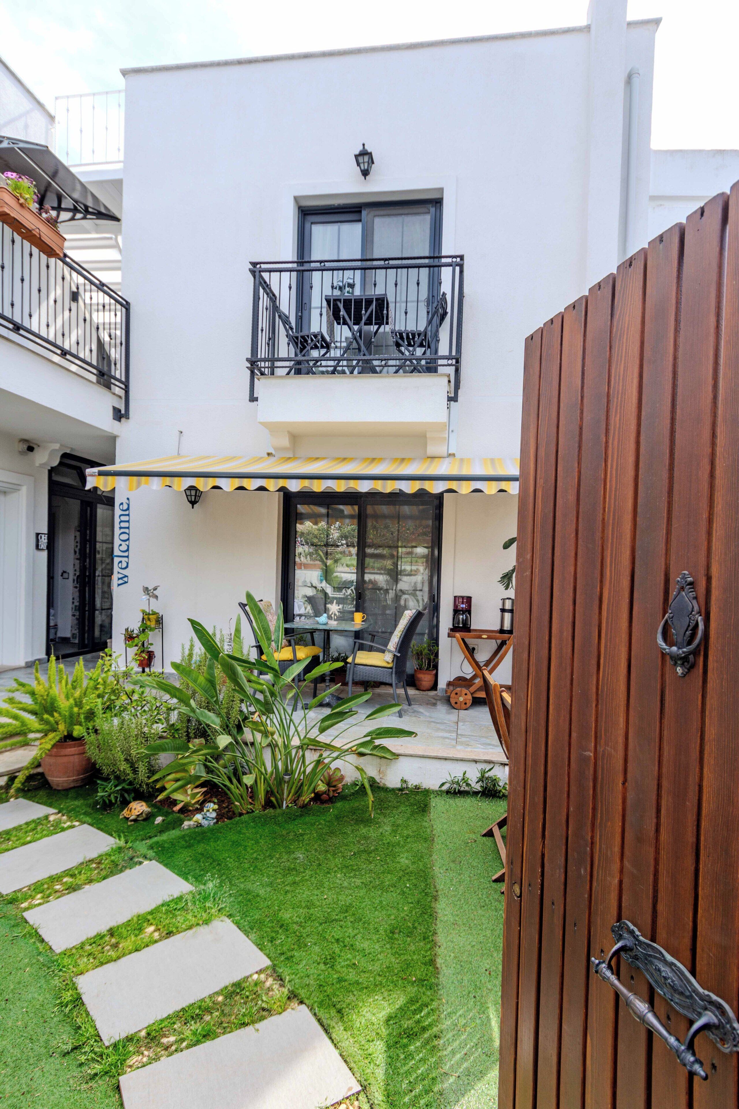 A two-story building with a balcony, a welcoming sign, and a wooden gate.