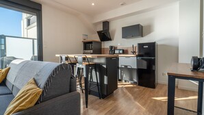 A modern apartment with a living area, kitchenette, and a balcony. - Charming apartment 200m from ocean with terrace and parking (Mimizan-Mimizan Plage)
