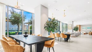 A modern dining area with a long table, comfortable chairs, and large windows offering a view of the cityscape. - FIRST CLASS | 1BR | Iconic Luxury (Dubai)