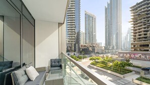 A modern apartment with a balcony overlooking a cityscape, featuring high-rise buildings and a landscaped area. - FIRST CLASS | 1BR | Iconic Luxury (Dubai)