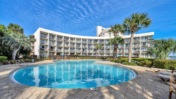 A hotel with a large pool surrounded by palm trees and a clear blue sky. - Charming waterfront studio in wonderful Fort Walton Beach, FL w/awesome pool (Fort Walton Beach)