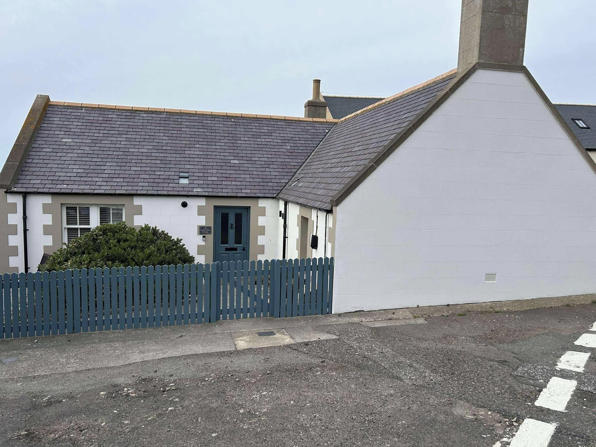A two-story house with a grey tiled roof and a white exterior.