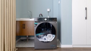 A compact, modern laundry room with a front-loading Hisense washer and dryer, a wooden cabinet, and a sink.
