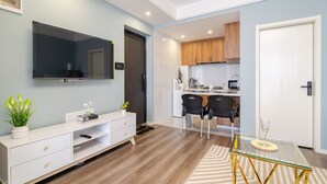 Eine moderne Küche mit Holzausstattung, einem Essbereich mit zwei Stühlen und einem an der Wand montierten Fernseher.