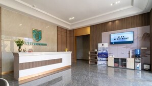 A hotel reception area with a modern design, featuring a reception desk, a digital screen displaying "ALBA APARTMENT," and a logo for "Alba Garden."