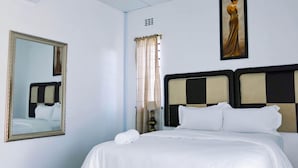 Una habitación de hotel con una cama grande, un espejo, un cuadro y un equipo de aire acondicionado.