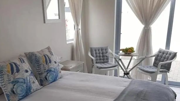 Un dormitorio con una cama grande, dos sillas, una mesita y una ventana con cortinas.