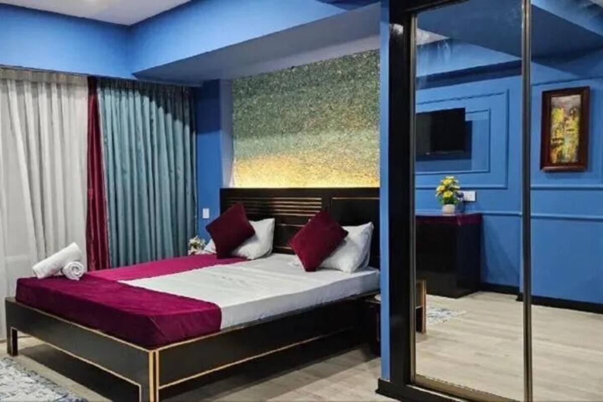 Une chambre à coucher moderne avec un lit, des rideaux et un tableau au mur.