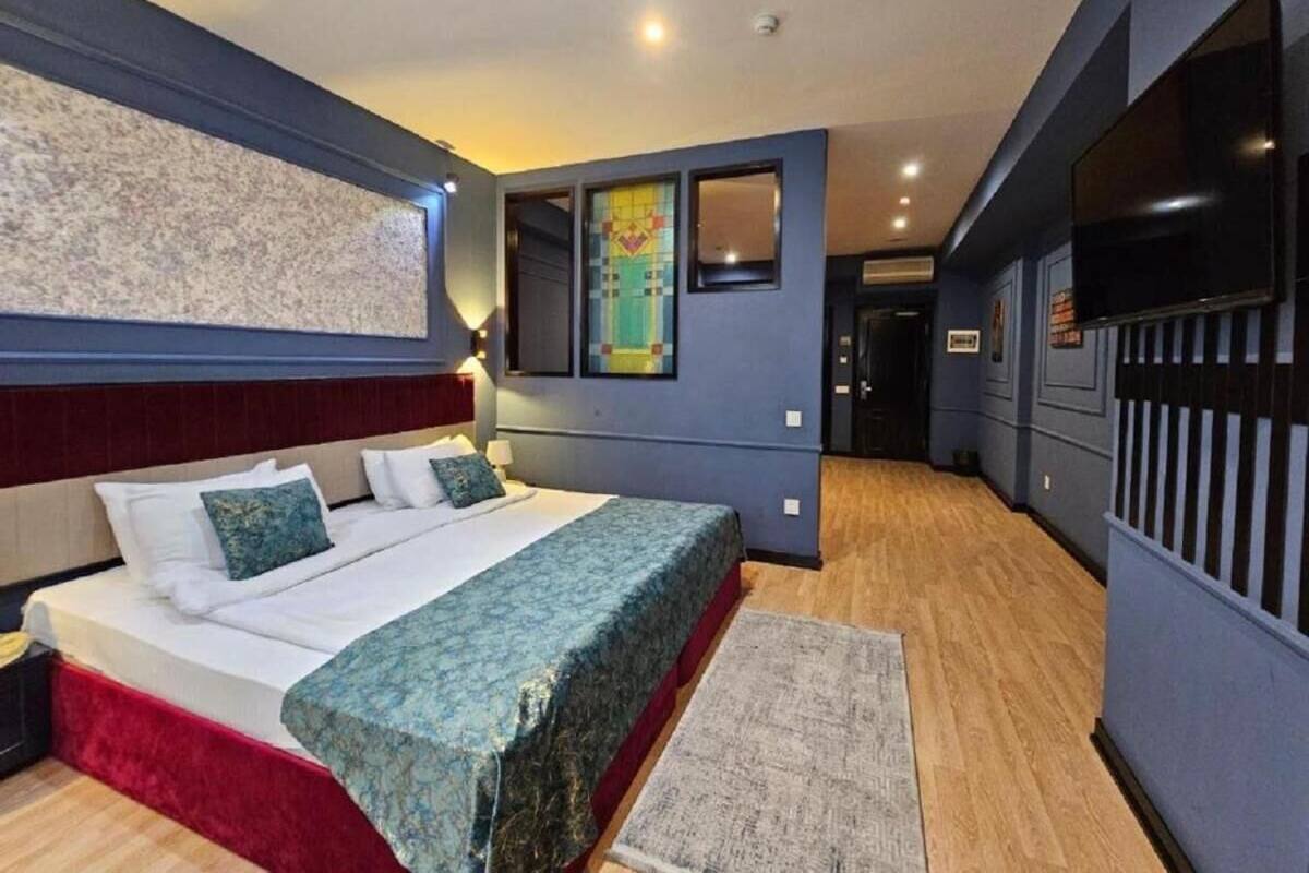 Une chambre d’hôtel avec un grand lit, un petit bureau, une télévision et une fenêtre donnant sur un beau paysage.