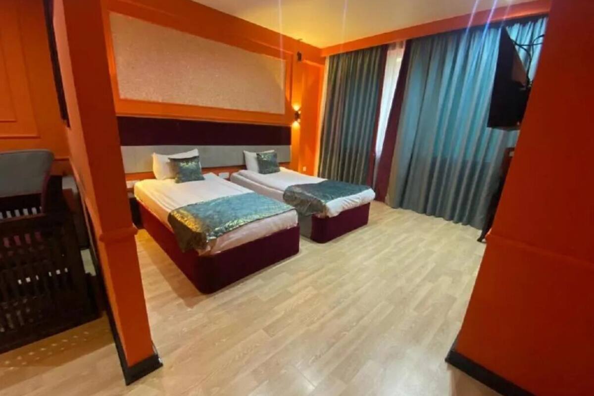 Une chambre d’hôtel avec deux lits, un bureau et une télévision.