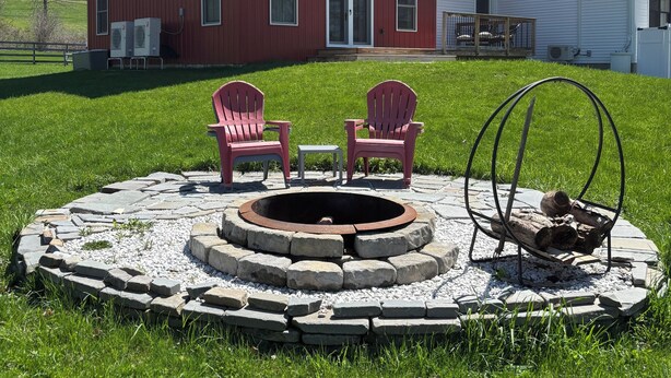 Ein rotes Haus mit Feuerschale und zwei Adirondack-Stühlen davor.