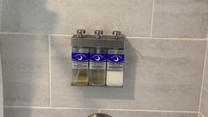 Ein Badezimmer mit Duschkopf, Seifenspender und Wasserhahn.