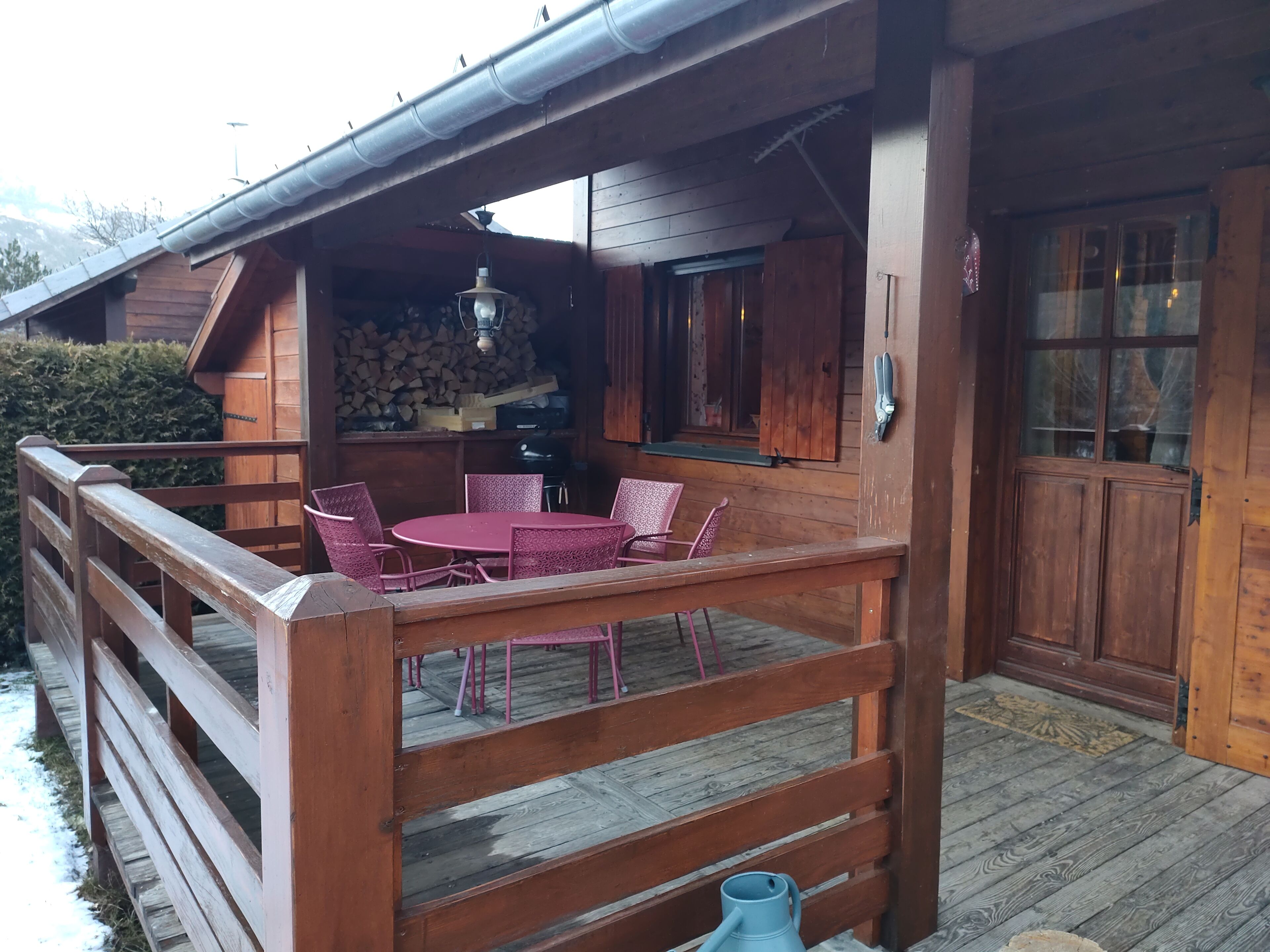 Une cabane en bois dotée d’un balcon, une table ronde avec des chaises et un luminaire suspendu.
