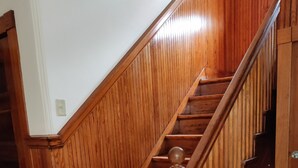 A wooden staircase with a handrail and a door at the bottom. - Historic 3-Bedroom Guest Suite · Prime Forest Park Location in Central West End (St. Louis)