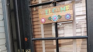 A black door with a wooden sign that reads "WELCOME" and decorative flowers. - Historic 3-Bedroom Guest Suite · Prime Forest Park Location in Central West End (St. Louis)