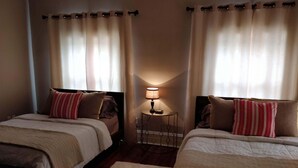 A hotel room with two beds, a small table with a lamp, and curtains. - Historic 3-Bedroom Guest Suite · Prime Forest Park Location in Central West End (St. Louis)