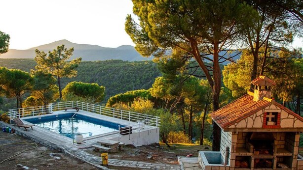 Una piscina con bordo bianco e un piccolo edificio con un simbolo di croce.