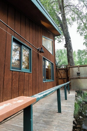 A wooden cabin with two windows, a bench, and a wooden deck. - Buena Vista Garden Studio Apartment: STR-043 (Buena Vista)