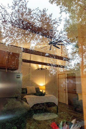 A bedroom with a bed, a nightstand, a lamp, and a window.