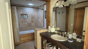 A bathroom with a wooden vanity, a large mirror, and a shower area.
