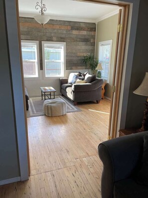 Una sala de estar con un sofá gris, una mesita y piso de madera.