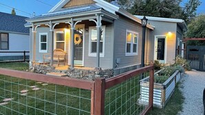 A single-story house with a porch, a number '213' on the door, and a fenced yard.