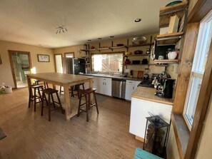 A kitchen with a wooden table and bar stools, a built-in oven, and a coffee machine.