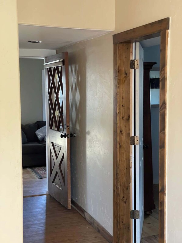 A doorway leading to a room with a dark-colored sofa and a patterned door.