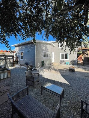 Una propiedad residencial con camino de entrada de grava, mobiliario exterior y un patio cubierto.