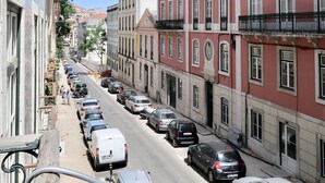 Une rue bordée de voitures garées et d’immeubles dotés de balcons.