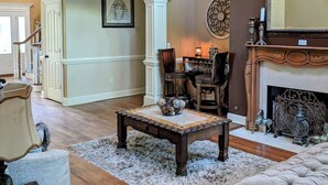 Un salon spacieux avec un haut plafond, une cheminée et un grand miroir.