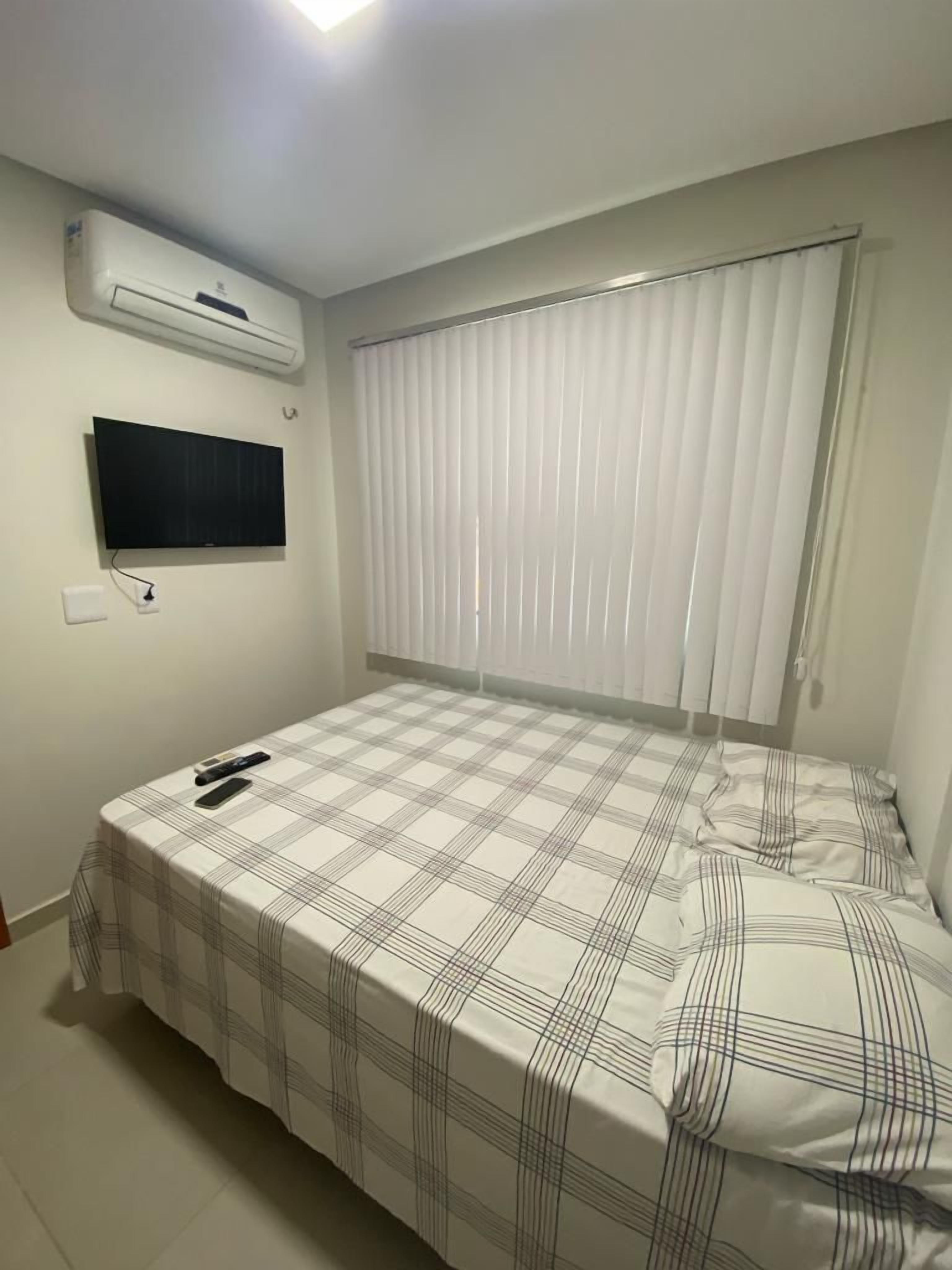 Ein Schlafzimmer mit einem Bett, einem an der Wand montierten Fernseher und einer Klimaanlage.