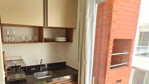 Eine moderne Küche mit Holzschränken, einer schwarzen Arbeitsplatte und einem Edelstahl-Spülbecken.