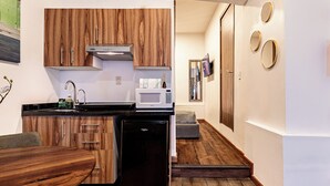 Una cocina compacta con armarios de madera, un microondas integrado y un refrigerador negro.