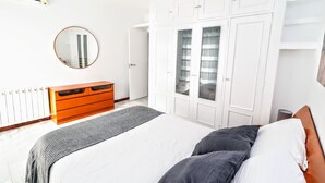Un dormitorio con cama, cómoda, armario, espejo y radiador.