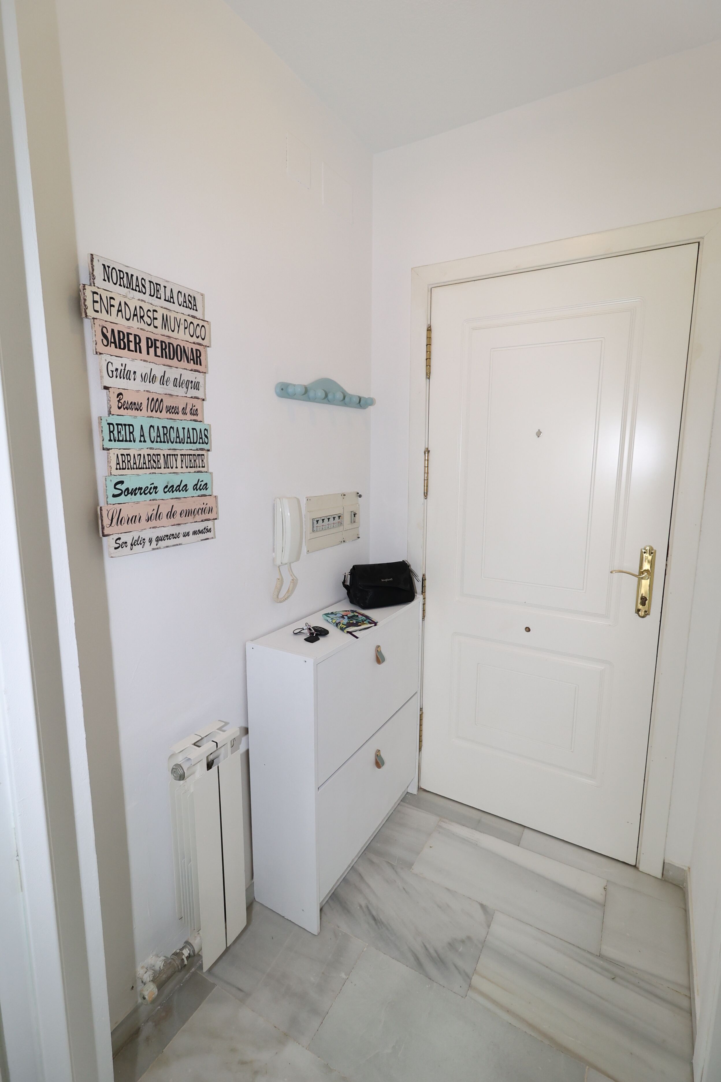 A white door with a brass handle, a white radiator, and a white cabinet with drawers.