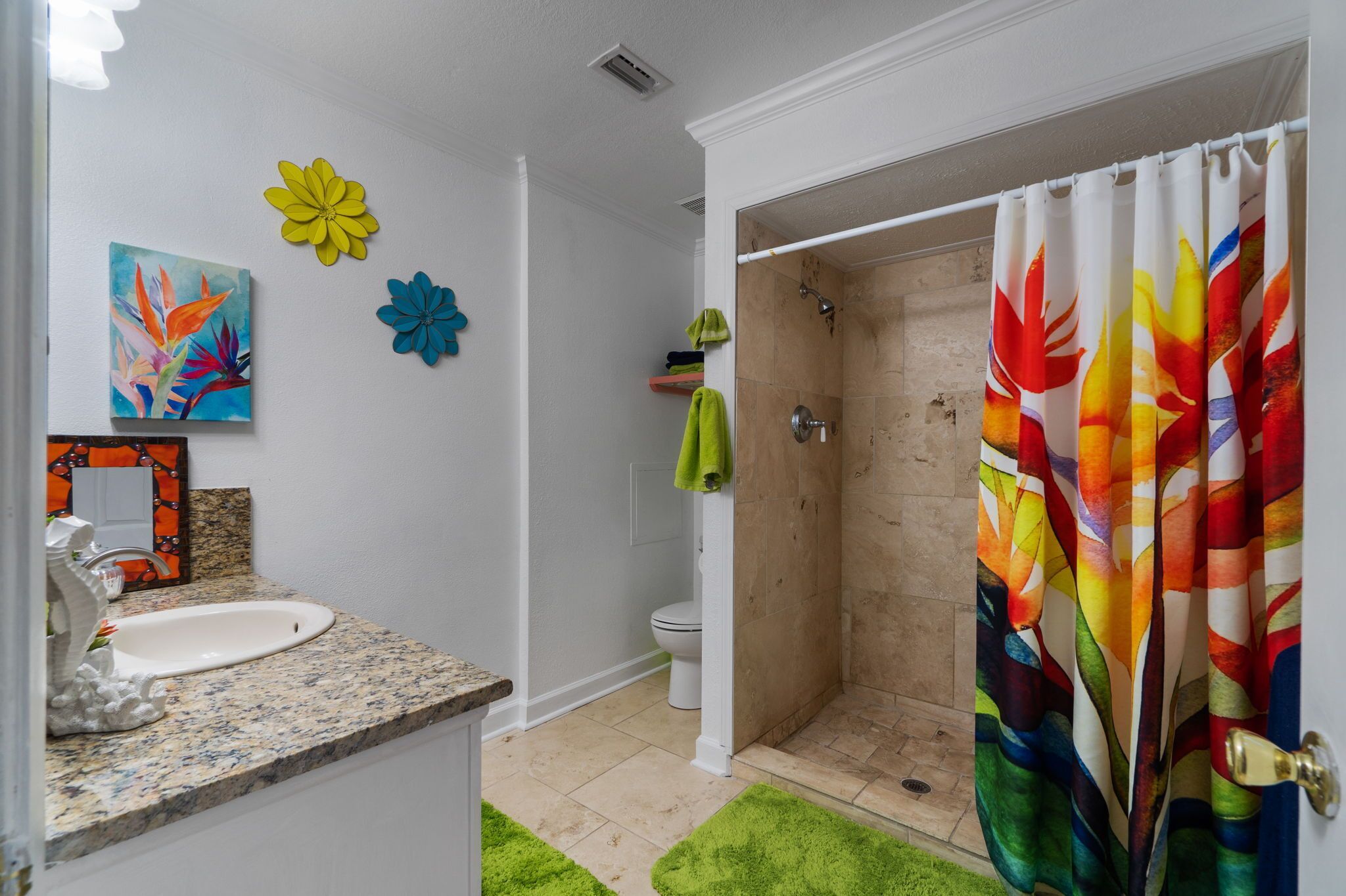 Un bagno con lavandino, toilette, doccia e tenda da doccia colorata.