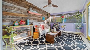 A cozy living room with a wooden wall, a ceiling fan, a white sofa, and a patterned rug. - Charming 2-bedroom suite in soothing Navarre with AC, WiFi (Navarre)