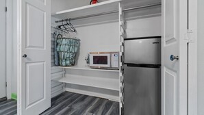 A compact kitchen with a built-in microwave, a stainless steel refrigerator, and a hanging rack for utensils. - Charming 2-bedroom suite in soothing Navarre with AC, WiFi (Navarre)