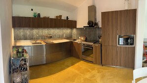 Eine moderne Küche mit Edelstahlgeräten, Holzschränken und einer gelb gefliesten Rückwand.