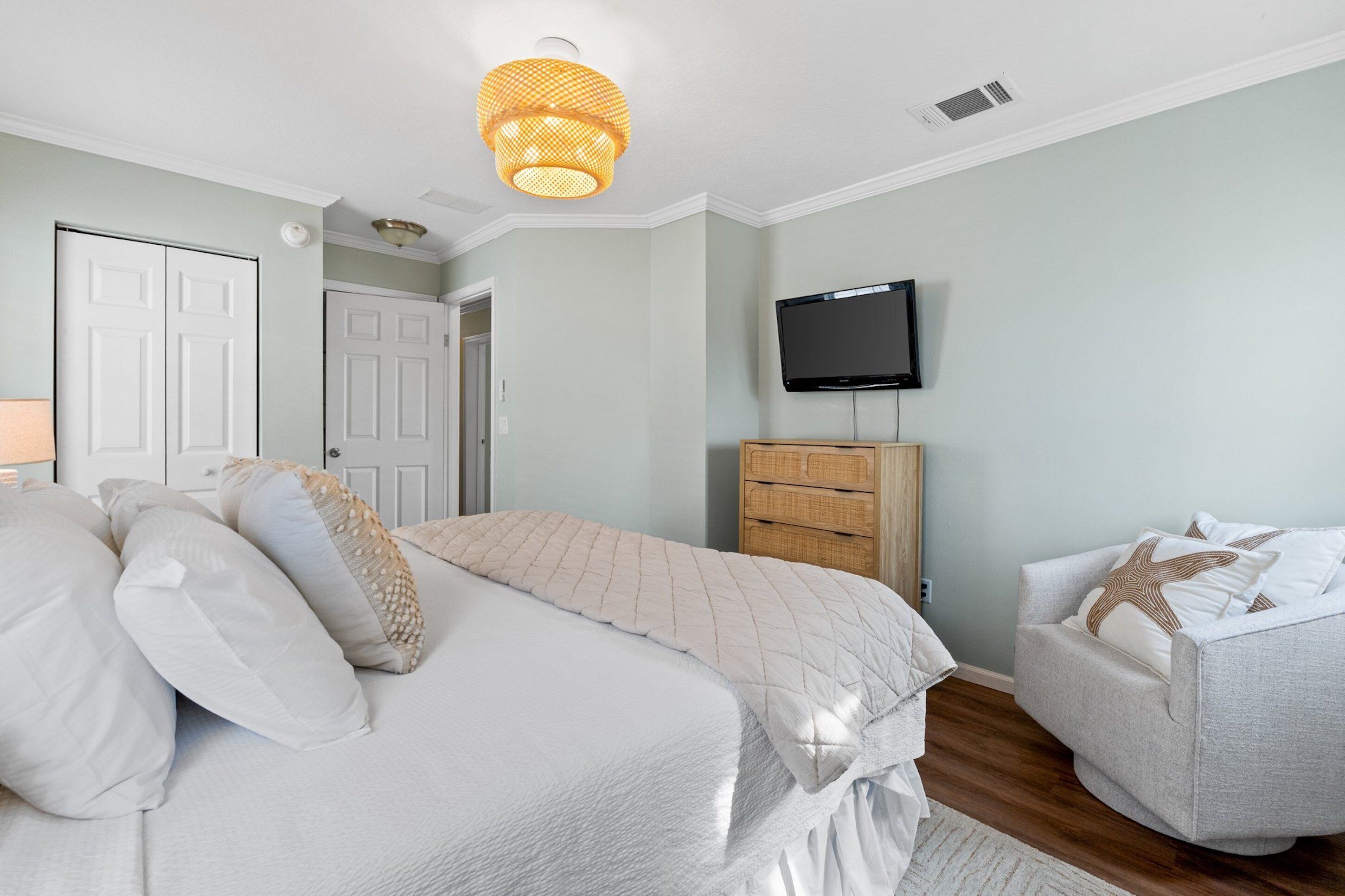 A bedroom with a bed, a television, a dresser, and a chair.