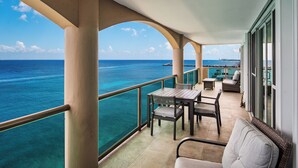 Un balcon avec vue sur l’océan, une table avec des chaises et un canapé.