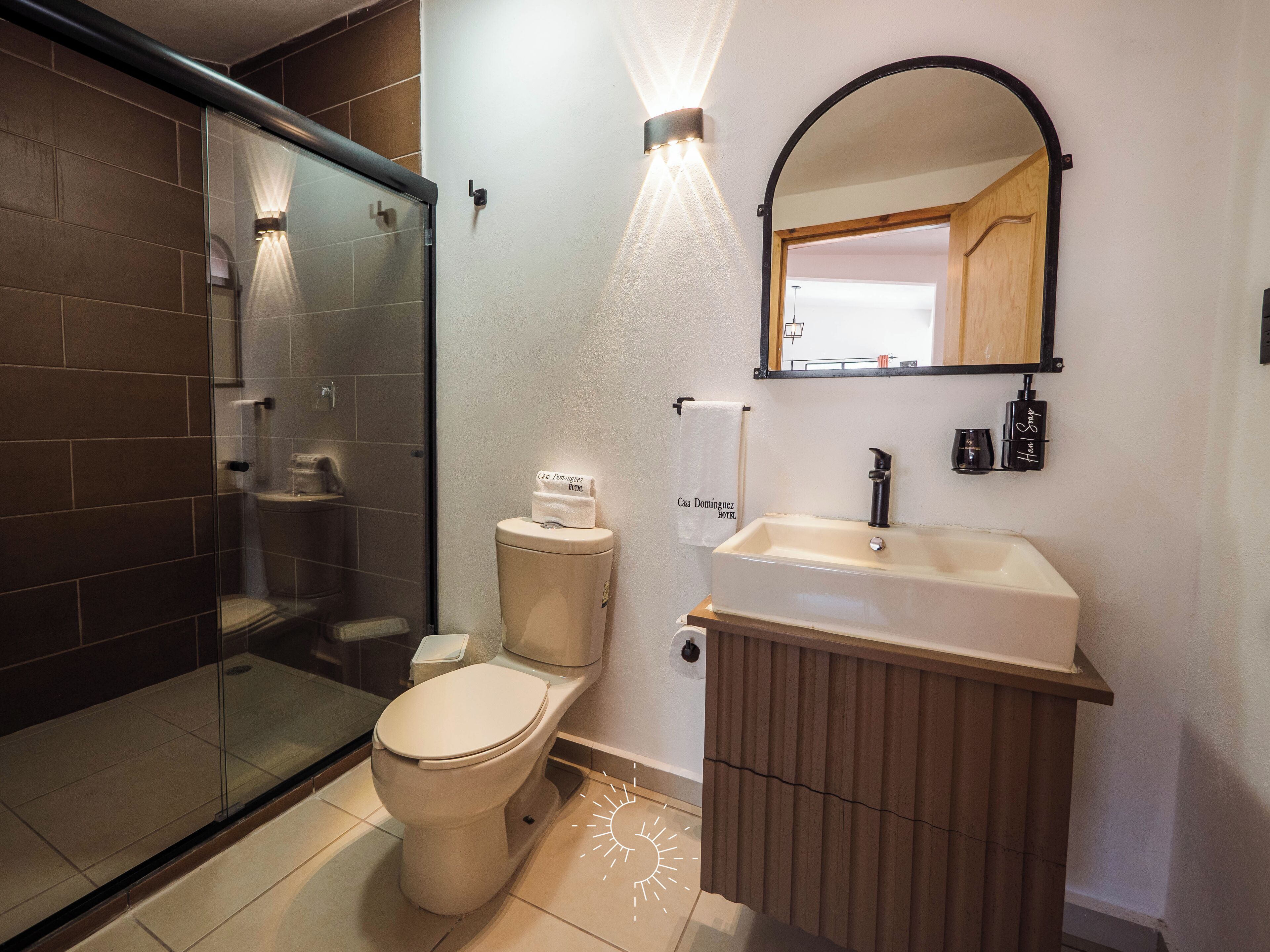 Une salle de bain moderne avec une douche à l’italienne en verre, des toilettes, un lavabo et un meuble-lavabo.