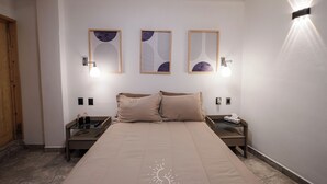 A bedroom with a large bed, two bedside tables, a nightstand, and wall-mounted artwork. - Hotel Casa Domínguez (Taxco)