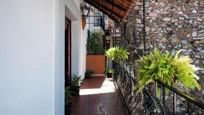 A narrow corridor with a tiled floor, a brick wall, and a metal railing. - Hotel Casa Domínguez (Taxco)