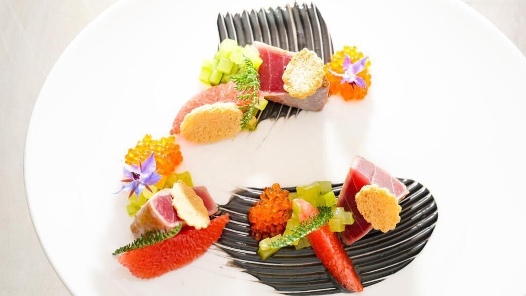 Plat blanc amb diversos aliments, com peix, caviar i guarnicions.
