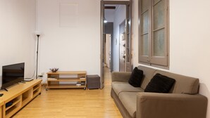 A living room with a TV, wooden entertainment unit, and a sofa with cushions. - PURE GRACIA, 2 bedrooms, excellent location (Barcelona)