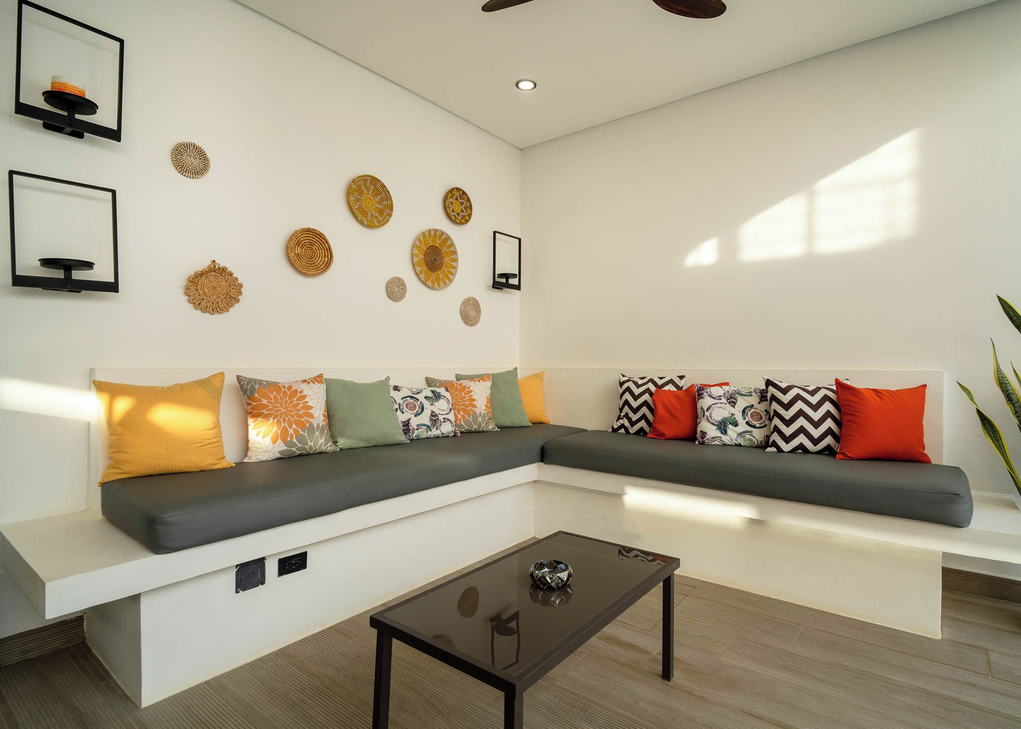 Una sala de estar moderna con un sofá modular, una mesa de centro de vidrio y decoración en la pared.