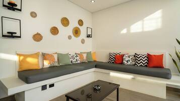 Una sala de estar moderna con un sofá modular, una mesa de centro de vidrio y decoración en la pared.
